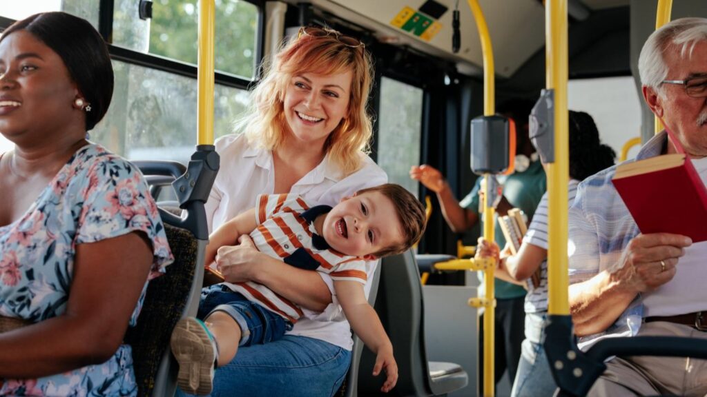 Zu sehen ist: eine Person fährt mit ihrem Kind Bus