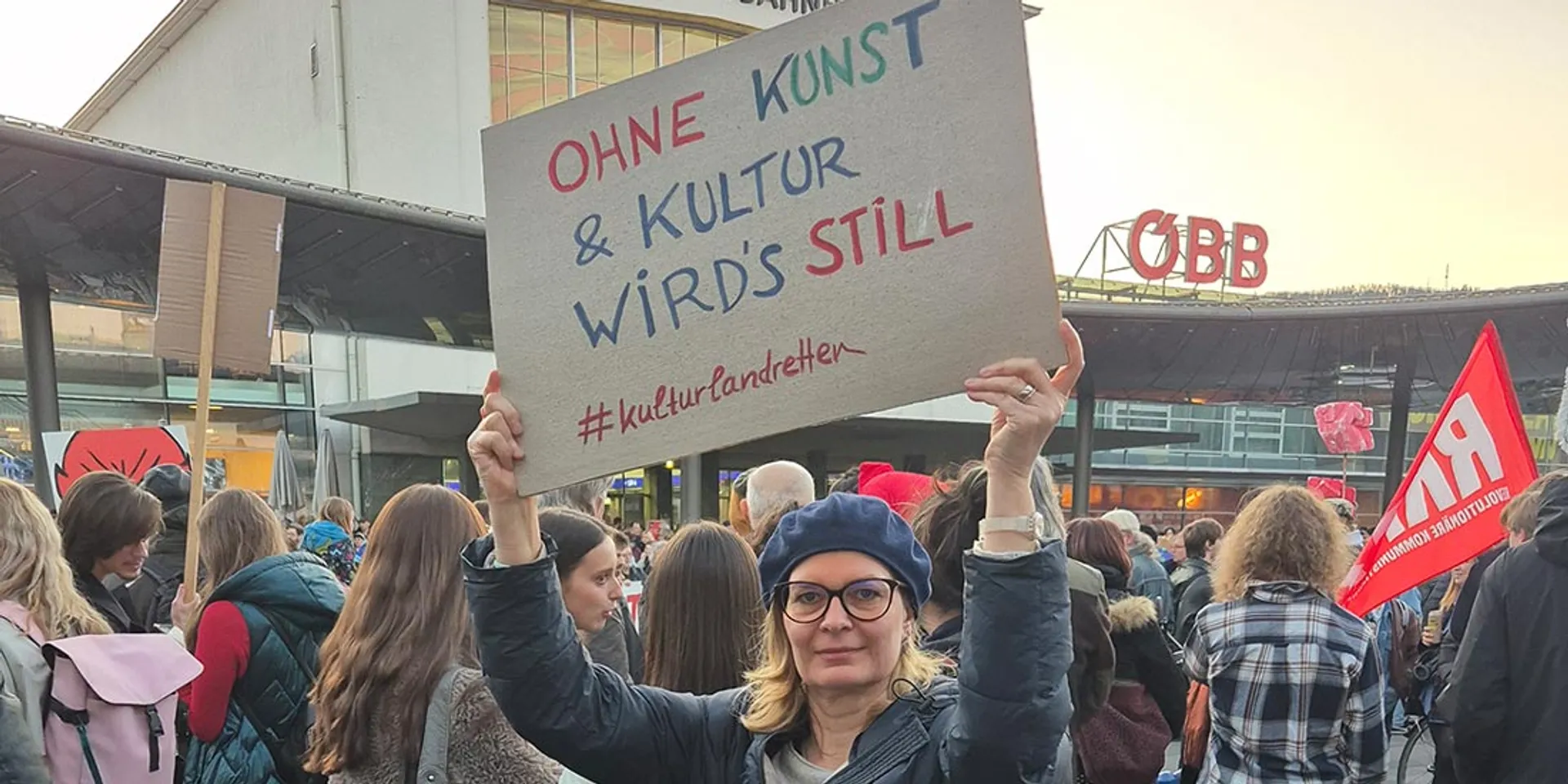 Landtagsabgeordnete Veronika Nitsche bei der Demo #kulturlandretten am Grazer Hauptbahnhof. Sie hält ein Schild: Ohne Kunst & Kultur wird's still.