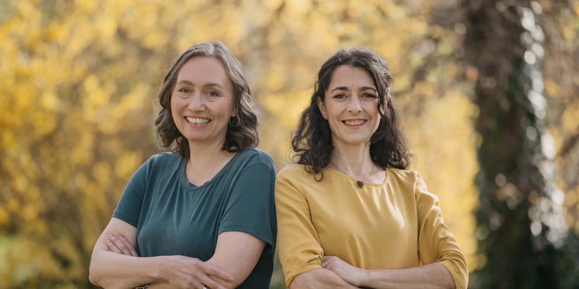Susanne Sinz und Sandra Krautwaschl Schulter an Schulter vor herbstlichem Wald