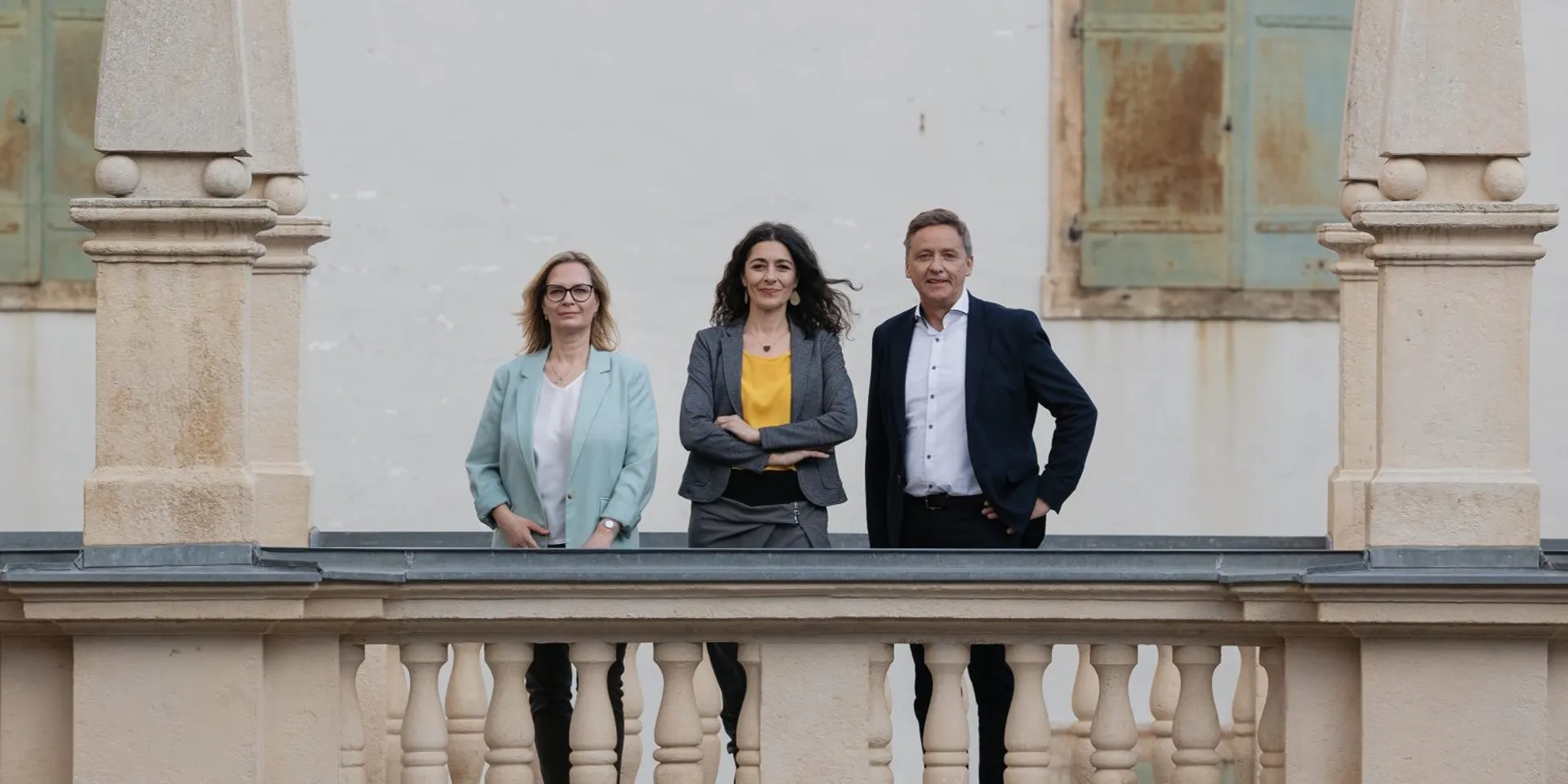 Landtagsabgeordnete Nitsche, Krautwaschl und Schönleitner stehen auf den Arkaden des Landhauses in Graz. Positiver Blick in die Kamera