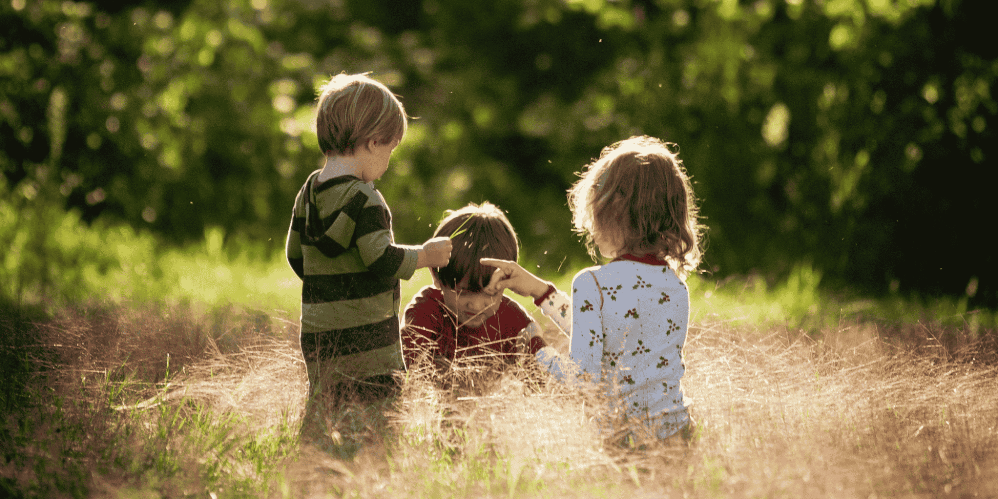 Drei Kinder spielen auf einer Wiese