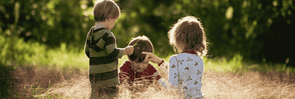 Drei Kinder spielen auf einer Wiese