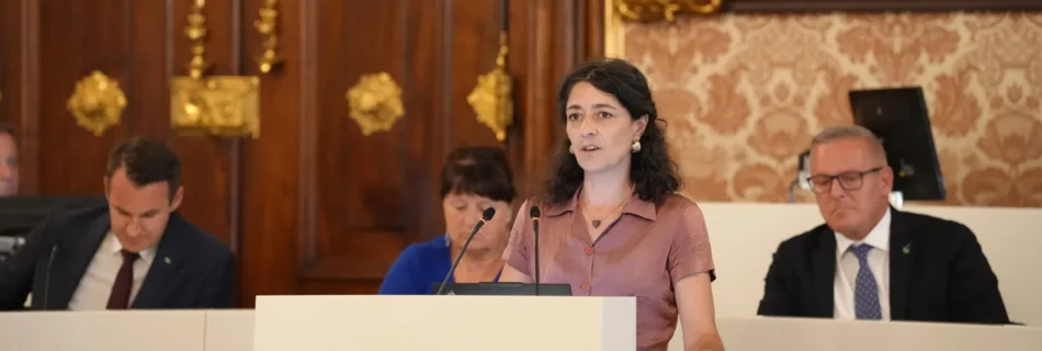 Klubobfrau Sandra Krautwaschl hält eine Rede am Rednerpult im Landtag Steiermark. Im Hintergrund sind weitere Politiker:innen zu sehen.