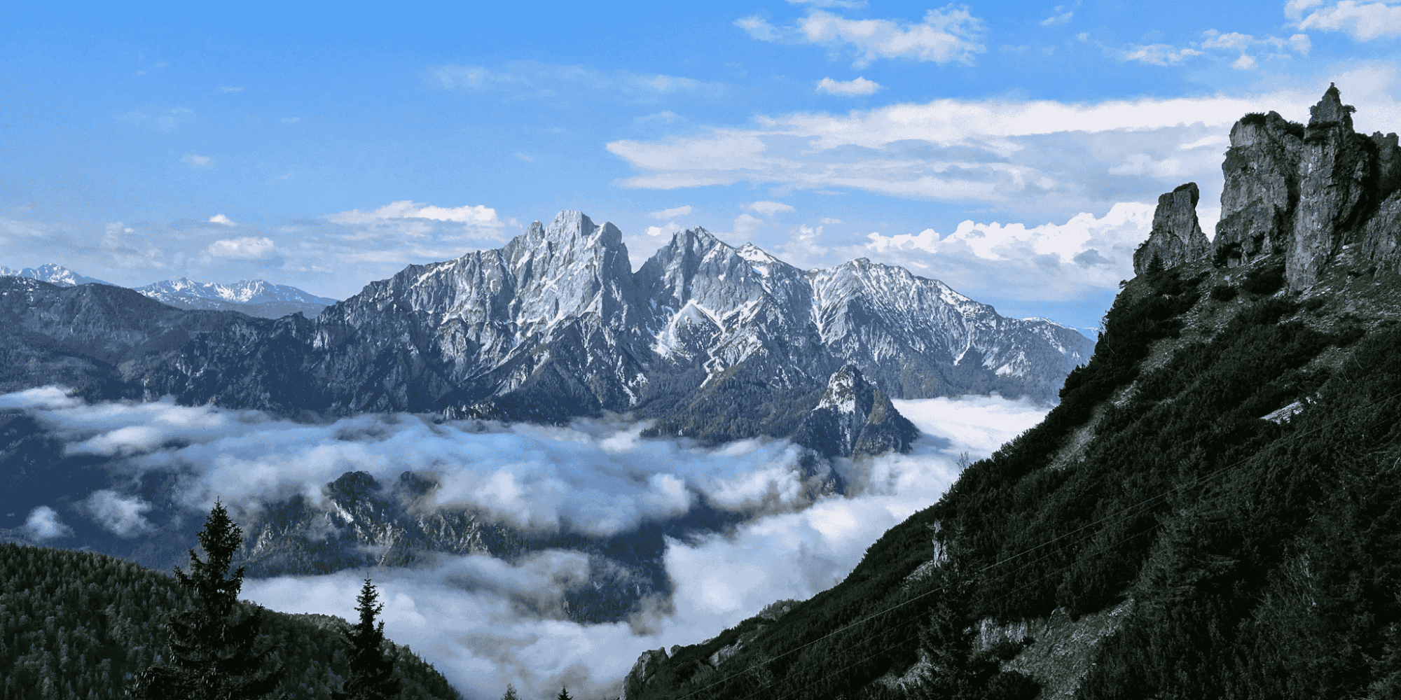 Spektakuläre alpine Berglandschaft des Naturpark Gesäuse mit Berggipfeln, die aus einem Wolkenmeer herausragen.