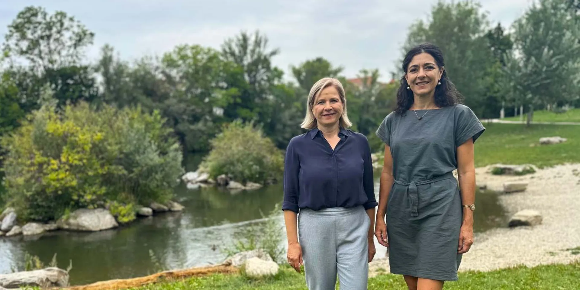 Sandra Krautwaschl und Judith Schwentner von den Grünen stehen am Ufer der Mur und setzen sich für das Flussbaden in der Steiermark ein.