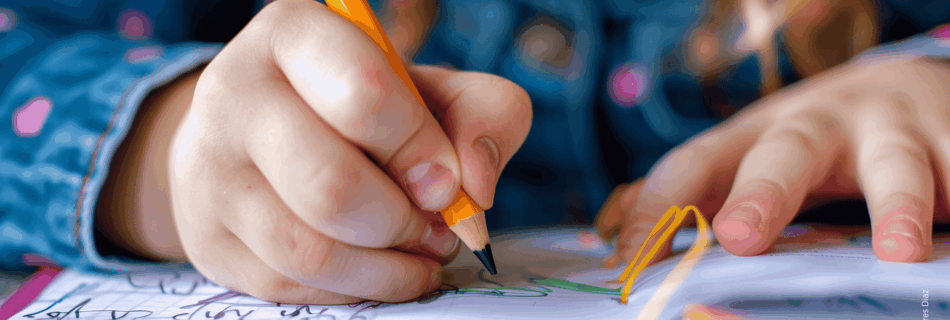 Kinderhände halten einen Stift mit schwarzer Spitze und zeichnen damit auf einem pinken Block mit weißen Blättern.