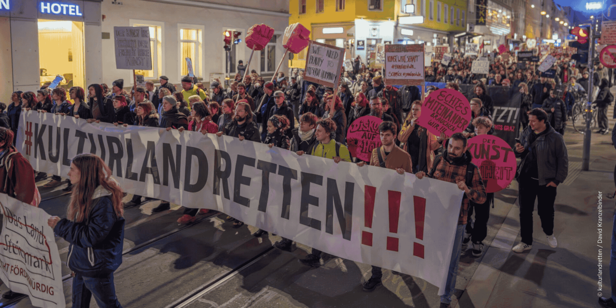 Demonstrant:innen in der Grazer Annenstraße mit großen Banner "#kulturlandretten!!!" und kleinen Demonstrationsschildern.
