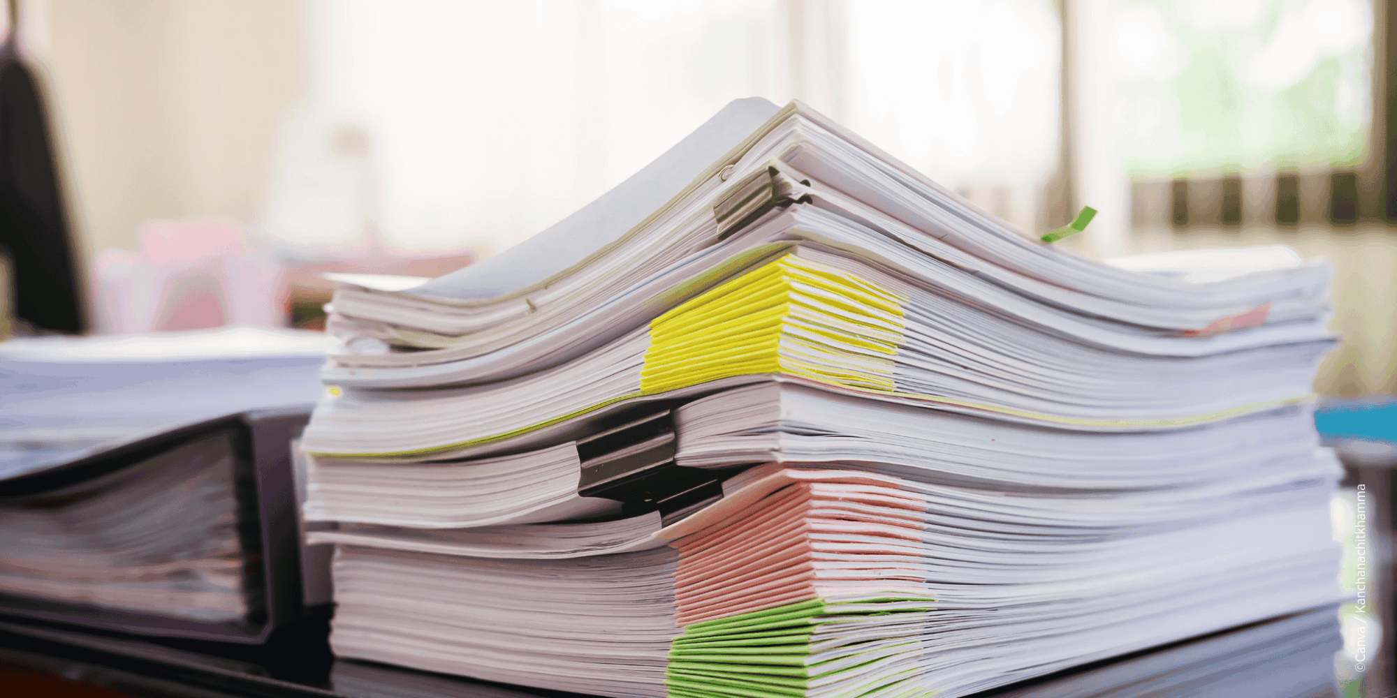 Hoher Aktenstapel symbolisiert Verwaltungsaufwand und fehlende Entlastung.