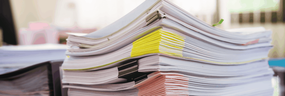 Hoher Aktenstapel symbolisiert Verwaltungsaufwand und fehlende Entlastung.