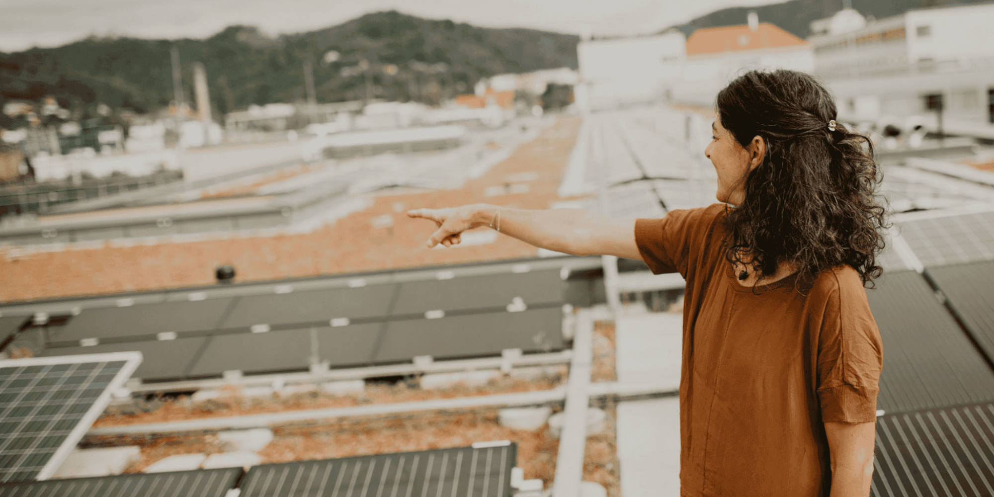 Sandra Krautwaschl auf Hallendach zwischen Photovoltaik-Paneelen, Symbolbild für den Ausbau von Dach-PV-Anlagen.