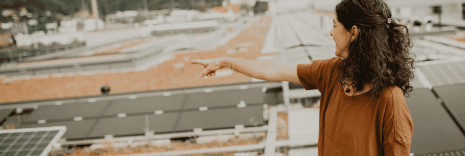 Sandra Krautwaschl auf Hallendach zwischen Photovoltaik-Paneelen, Symbolbild für den Ausbau von Dach-PV-Anlagen.