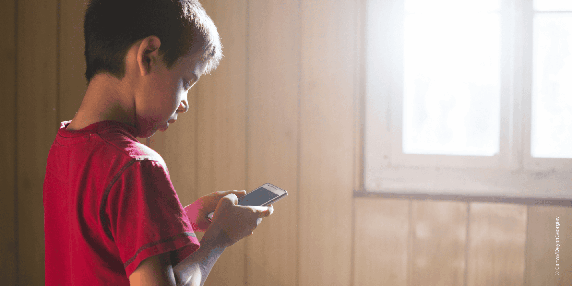 Kleines Kind hält Smartphone in der Hand und blickt auf den Bildschirm