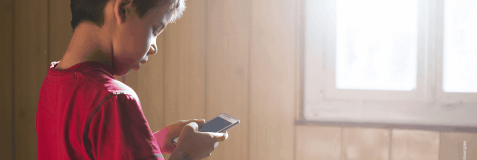 Kleines Kind hält Smartphone in der Hand und blickt auf den Bildschirm