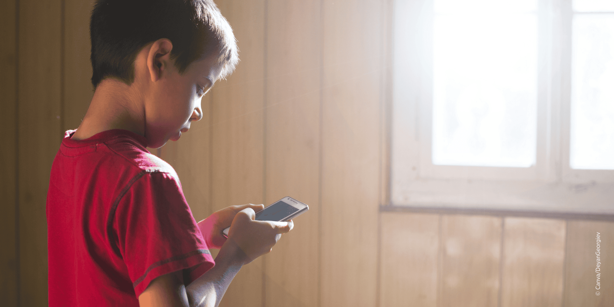 Kleines Kind hält Smartphone in der Hand und blickt auf den Bildschirm