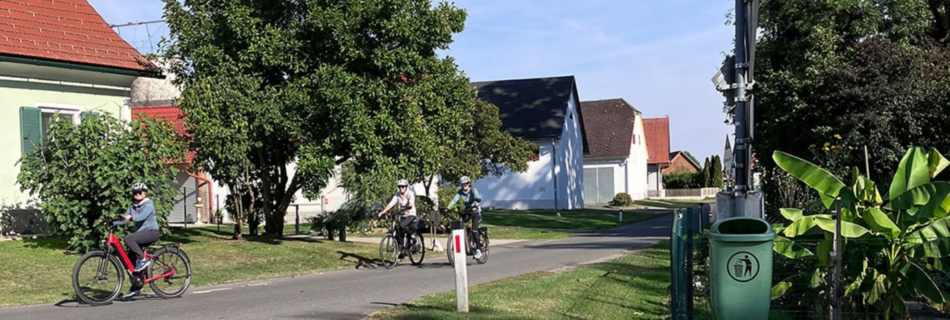 Radfahrer:innen auf der schmalen Ortsstraße in Donnersdorf, Gemeinde Halbenrain